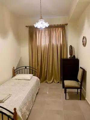a bedroom with a bed and a chair and a window at DS Apartment (semi-basement) in Athens