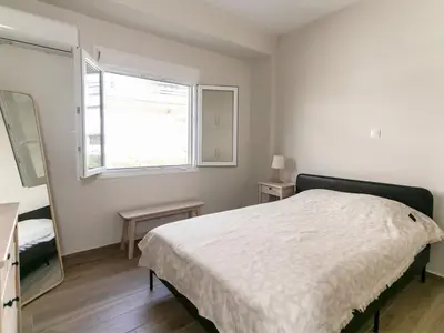 a bedroom with a white bed and a window at Zesto spitiko in Piraeus