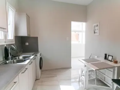 a white kitchen with a sink and a table at Zesto spitiko in Piraeus