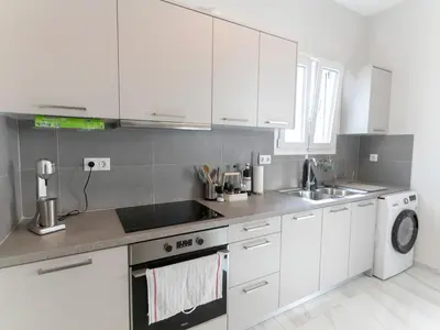 a kitchen with white cabinets and a sink and a dishwasher at Zesto spitiko in Piraeus