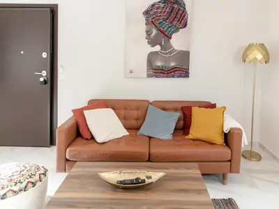 a living room with a brown couch with colorful pillows at Zesto spitiko in Piraeus