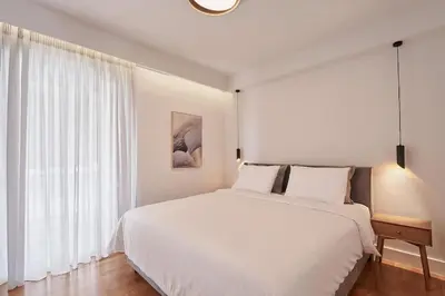 a white bedroom with a large bed and a window at A Sunkissed retreat under the Acropolis in Athens