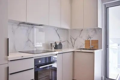 a white kitchen with white cabinets and a sink at A Sunkissed retreat under the Acropolis in Athens
