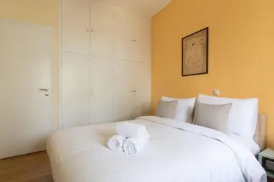 a bedroom with a white bed with towels on it at Tati's Parthenon apt 2bdr with balcony in Athens