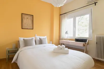 a bedroom with a large white bed with a window at Tati's Parthenon apt 2bdr with balcony in Athens