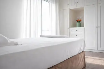 a white bedroom with a large bed and a window at Acropolis Area Large 3BR 2BA Apartment in Athens