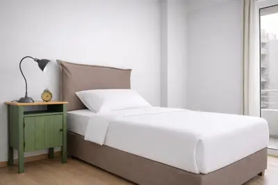 a bedroom with a white bed and a night stand at Acropolis Area Large 3BR 2BA Apartment in Athens