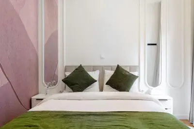 a bedroom with a large bed with green sheets and pillows at Lux 2 bedroom apt next to metro in Athens