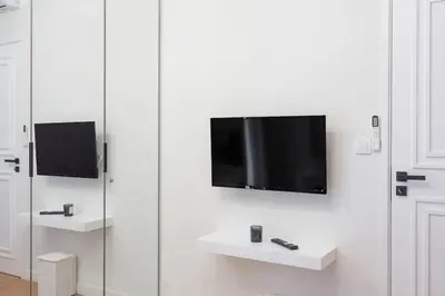a flat screen tv hanging on a white wall at Lux 2 bedroom apt next to metro in Athens