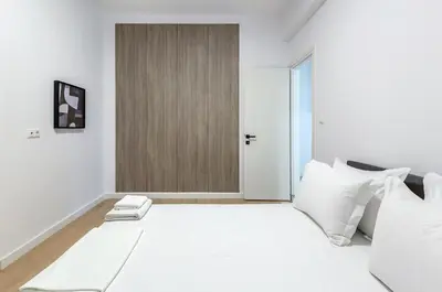 a white bedroom with a large bed with white pillows at Downtown City Apartment in Athens