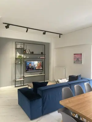 a living room with a blue couch and a tv at Downtown City Apartment in Athens
