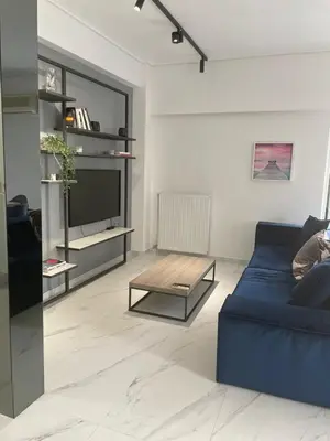 a living room with a blue couch and a coffee table at Downtown City Apartment in Athens
