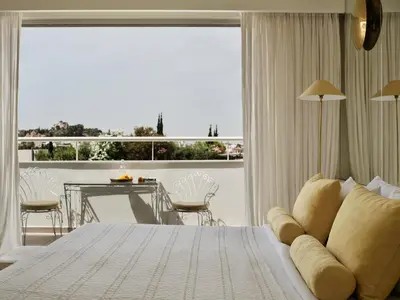 a bedroom with a bed and a table and a large window at Apollo Palm Hotel in Athens