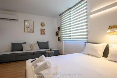 a bedroom with a white bed and a couch at Nesto Athens Airport Zen in Spáta