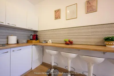 a kitchen with white cabinets and a counter with stools at Nesto Athens Airport Zen in Spáta