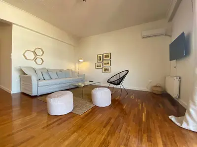 a living room with a couch and two white stools at 2-bedroom apartment in Athina (Filopappou) in Athens