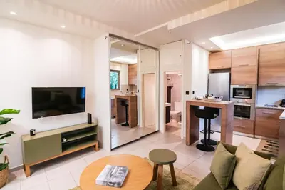 a living room with a couch and a tv and a kitchen at AlMar- Διαμέρισμα στο κέντρο της Ηλιούπολης in Athens