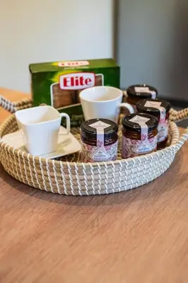 a basket of jam and cups on a table at AlMar- Διαμέρισμα στο κέντρο της Ηλιούπολης in Athens