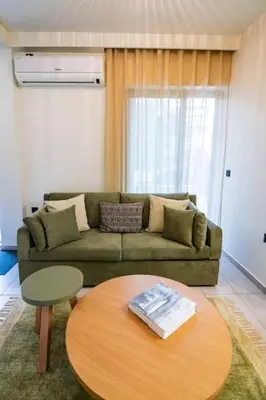 a living room with a green couch and a table at AlMar- Διαμέρισμα στο κέντρο της Ηλιούπολης in Athens