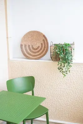 a green chair and a plant on a wall at AlMar- Διαμέρισμα στο κέντρο της Ηλιούπολης in Athens