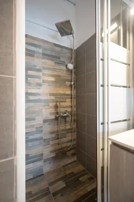 a bathroom with a shower with a wooden wall at Athens center 1 bedrm 4 pers apartment by MPS in Athens