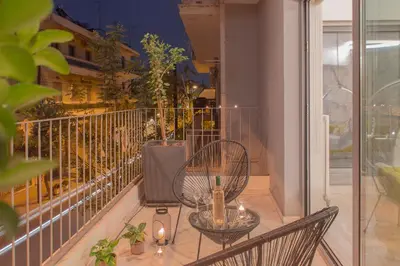 a balcony with two chairs and a table with a bottle of wine at Living Stone Bronze in Athens