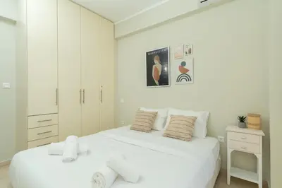 a white bedroom with a large bed with towels on it at Blanco Apartment by A&D Properties in Porto Rafti