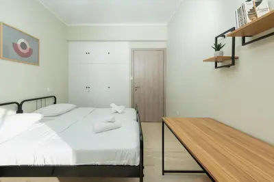 a bedroom with a white bed and a wooden table at Blanco Apartment by A&D Properties in Porto Rafti