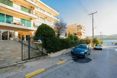 a blue car parked in a parking lot next to a building at Blanco Apartment by A&D Properties in Porto Rafti