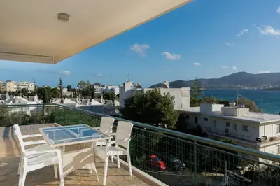 a balcony with a table and chairs and a view of the water at Blanco Apartment by A&D Properties in Porto Rafti