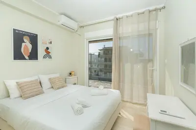 a bedroom with a white bed and a window at Blanco Apartment by A&D Properties in Porto Rafti