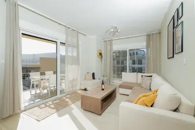 a living room with a white couch and a large window at Blanco Apartment by A&D Properties in Porto Rafti