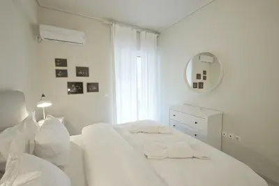 a white bedroom with a white bed and a mirror at LucyZen! Stylish Apt, Athenian Riviera, near beach in Athens