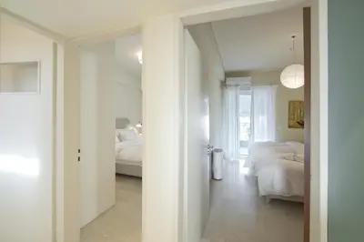 a white room with two beds and a hallway at LucyZen! Stylish Apt, Athenian Riviera, near beach in Athens