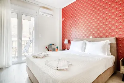 a bedroom with a large bed with a red wall at Nemesis - Elegant apartment in Athens in Athens
