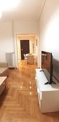 a living room with a television on a wooden floor at Modern home, 6' from the Metro in Athens