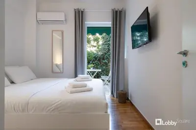 a white bedroom with a bed and a window at Aether Apartment by LobbySquare in Athens