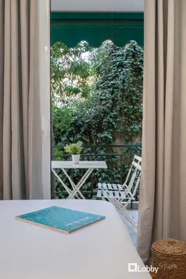 a table and chair on a balcony with a window at Aether Apartment by LobbySquare in Athens