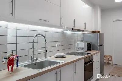 a white kitchen with a sink and a microwave at Aether Apartment by LobbySquare in Athens