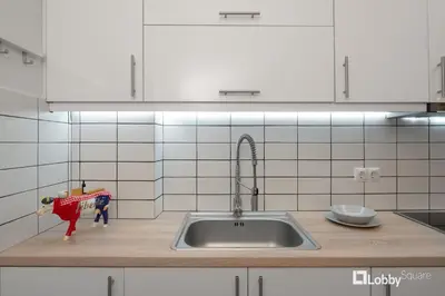 a kitchen counter with a sink and white cabinets at Aether Apartment by LobbySquare in Athens