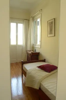 a bedroom with two beds and a table and two windows at SUNNY QUIET APATMENT AT LYCABETOUS in Athens