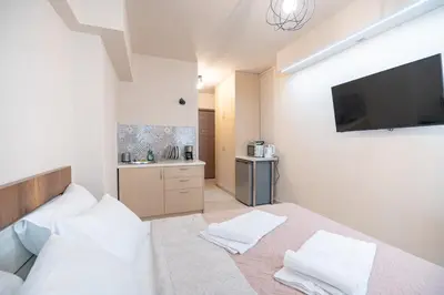 a bedroom with a bed with white pillows and a television at Monastiraki metro st studio for 2 persons by MPS in Athens