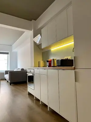 a kitchen with white cabinets and a couch in a room at Mosaikon Guesthouses #Nikiou Str in Athens