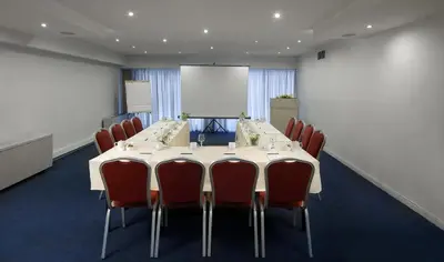 a conference room with a table and chairs and a whiteboard at Airotel Parthenon in Athens