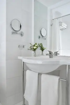 a white bathroom with a sink and two mirrors at Airotel Parthenon in Athens