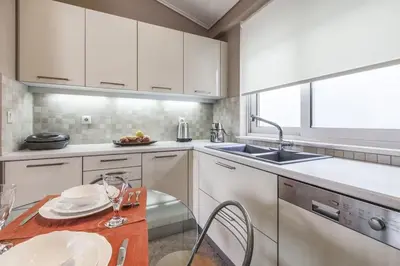 a kitchen with white cabinets and a wooden table at Luxury Acropolis View Duplex Penthouse in Thiseio 155m2 in Athens