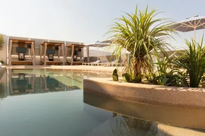 a swimming pool with plants and an umbrella next to a building at Airotel Alexandros in Athens