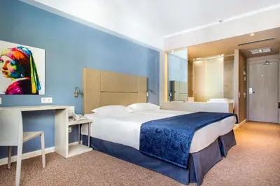 a hotel room with a large bed and a desk at Airotel Alexandros in Athens