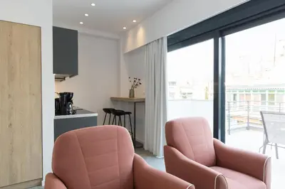 a living room with two pink chairs and a kitchen at Voda Luxury Residence Penthouse #601 - Acropolis View Rooftop in Athens