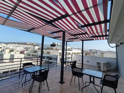 a patio with tables and chairs under a red and white umbrella at Voda Luxury Residence Penthouse #601 - Acropolis View Rooftop in Athens